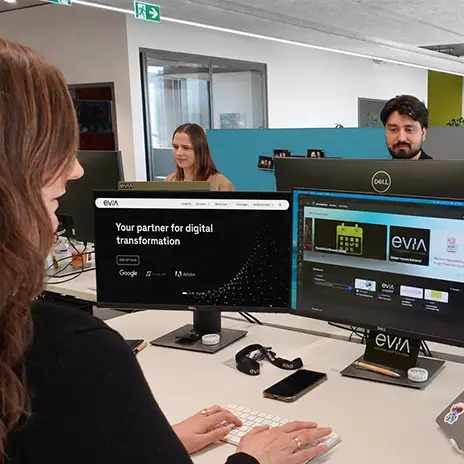 Two people are working together on a laptop. One of them is explaining something to the other.